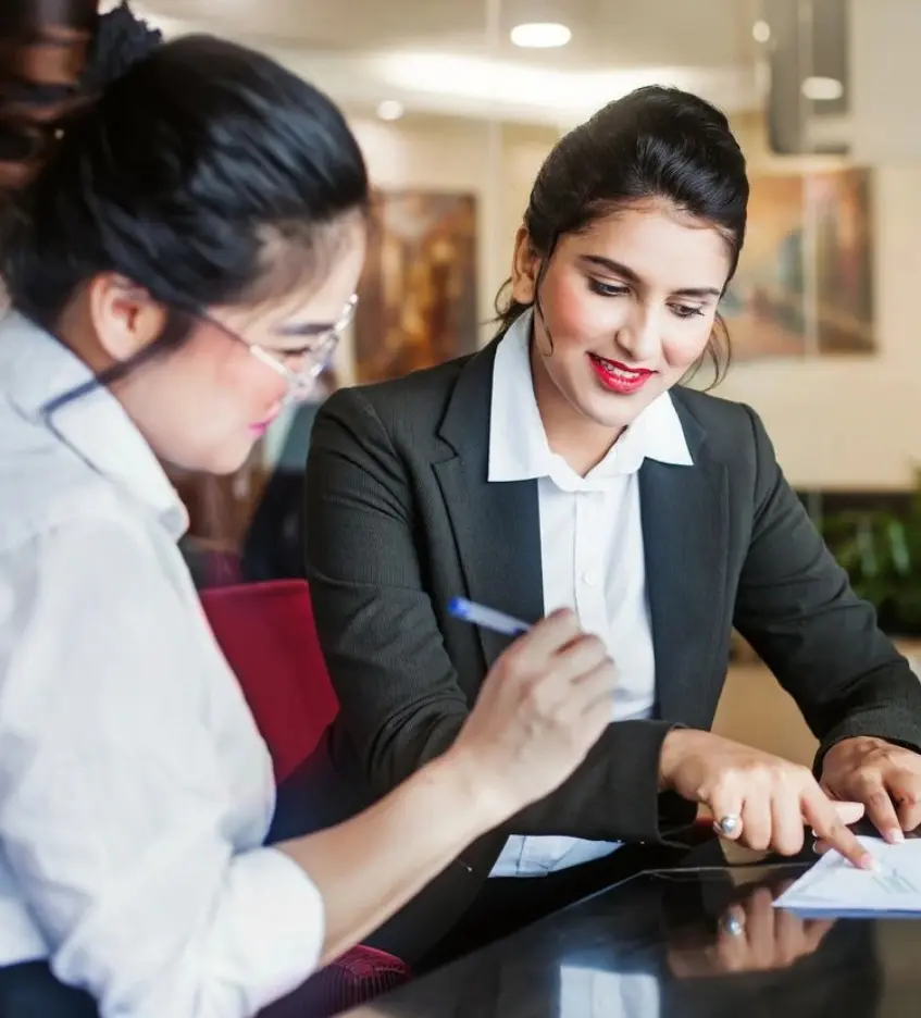 Two women sitting at a table working on papers.