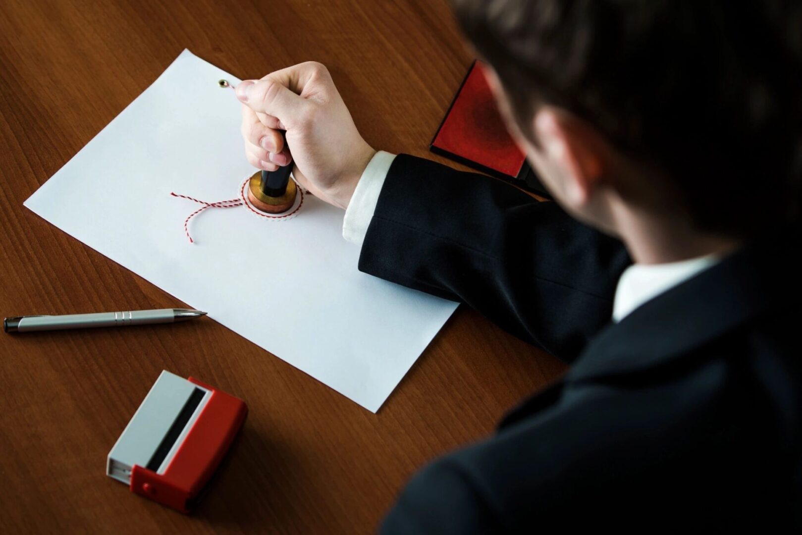 A man in a suit and tie sitting at a table with a stamp.