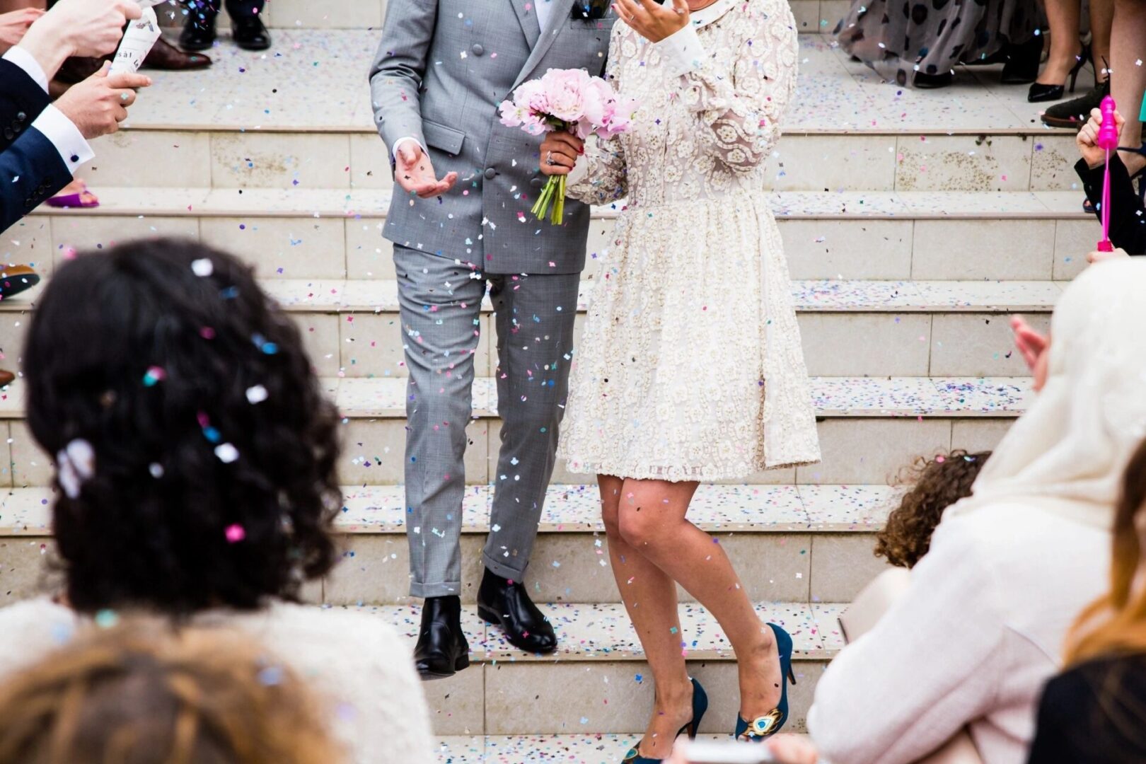 A man and woman standing on steps holding flowers.